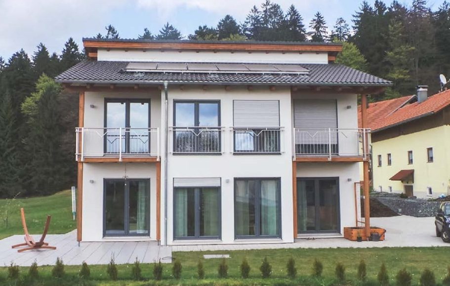 Der Hausbau Berater - Drevo Fertighaus Berater Modernes zweigeschossiges Haus mit schwarzem Dach und roter Seitenwand.