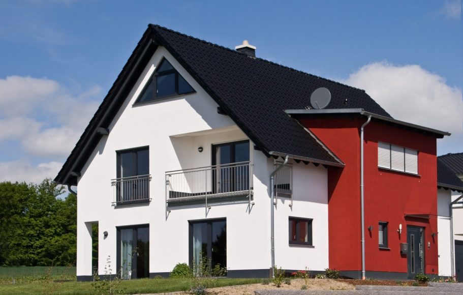Der Hausbau Berater - Kundenhaus Modernes zweigeschossiges Haus mit schwarzem Dach und roter Seitenwand.