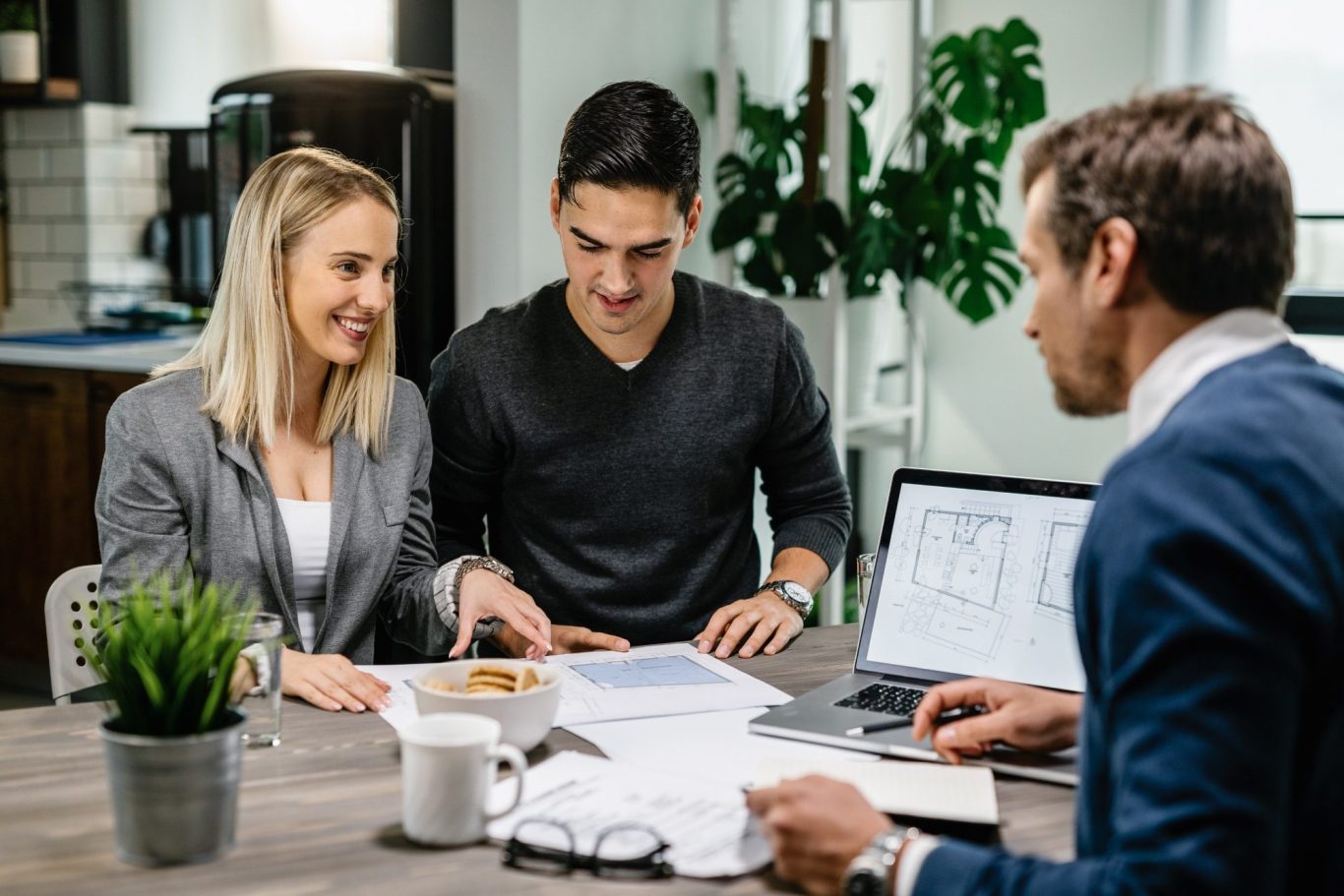 Fachberatung mit Th. Bärtle - Der Hausbau Berater - Fachberater für Fertighäuser Drei Personen beraten sich an einem Tisch, Unterlagen und Laptop sind auf dem Tisch.