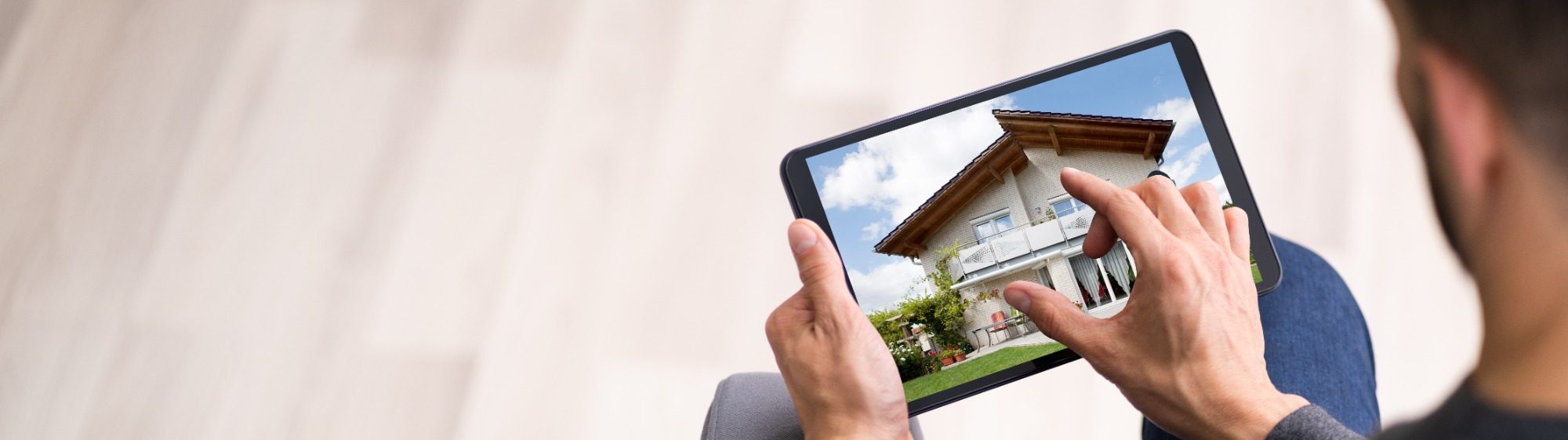 Der Hausbau Berater - Fertighaus Fachberater - Th. Bärtle Person betrachtet ein Tablet mit einem Bild eines Hauses.