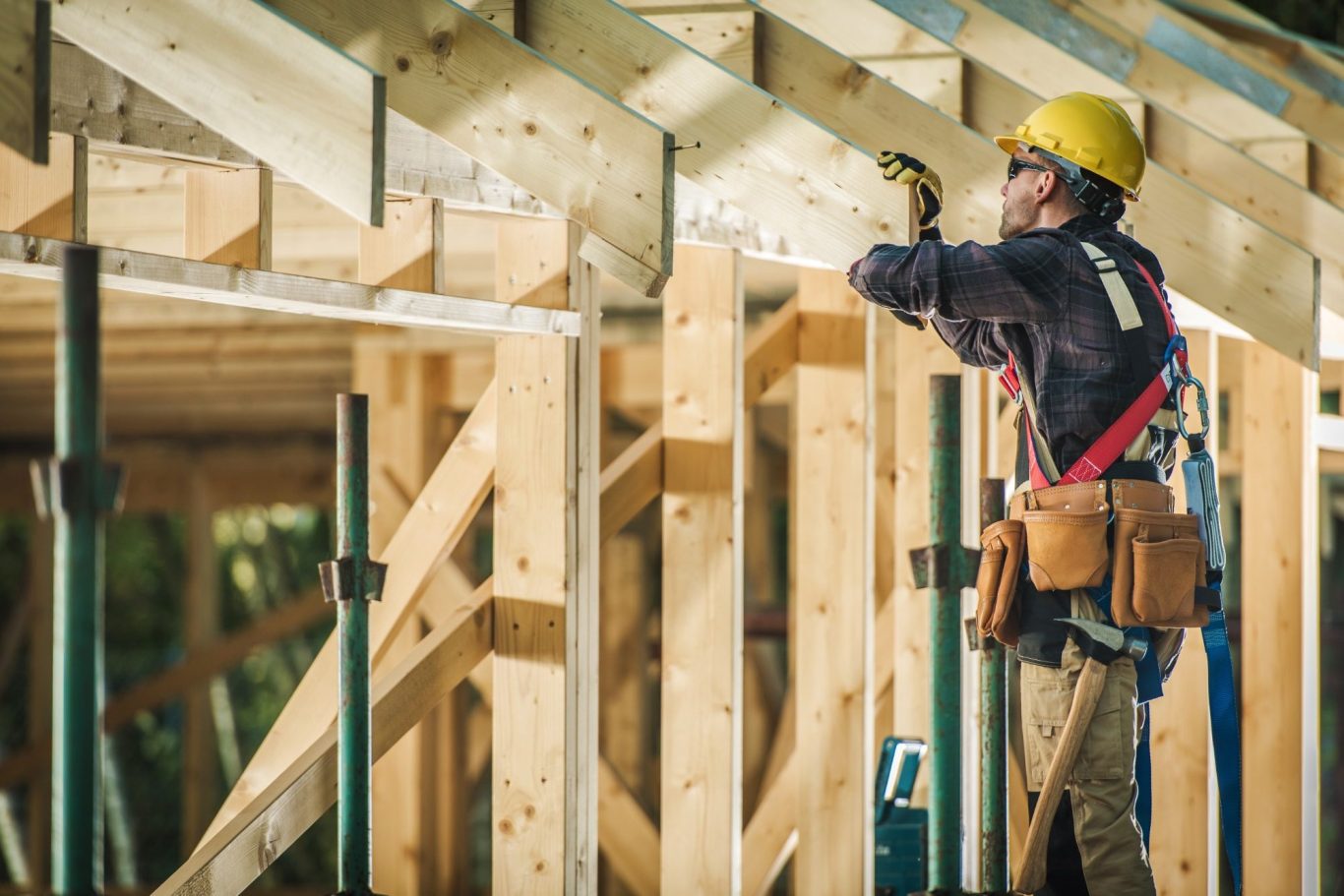 Der Hausbau Berater - Fachberater für Fertighäuser - Thomas Bärtle Bauarbeiter mit Helm, der an einer Holzstruktur arbeitet.