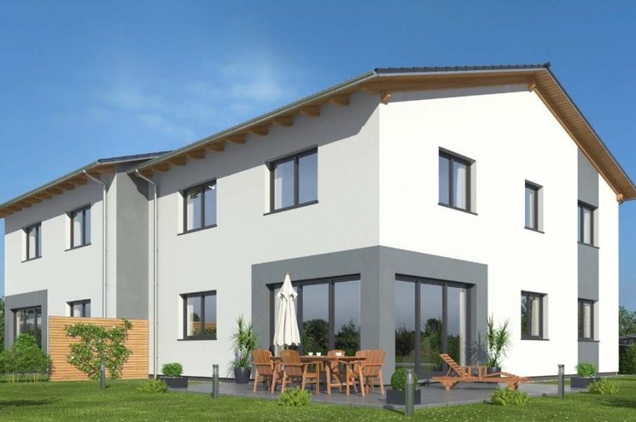 Modernes Haus mit Terrasse, Gartenmöbeln und Sonnenschirm, in sonniger Umgebung.