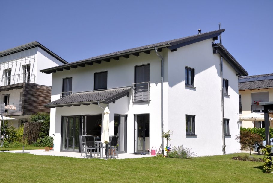 Der Hausbau Berater - Fachberater für Fertighäuser - Thomas Bärtle Weißes zweistöckiges Haus mit Garten und Terrasse.